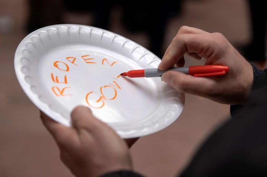 Un trabajador federal escribe un mensaje en un plato de plástico durante una marcha que pide el fin del cierre parcial del Gobierno de EEUU.