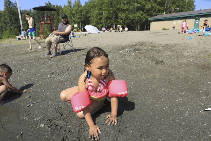 Milana Acuña, de 5 años, juega con el lodo en la playa en el lago Goose mientras su padre, Manny Acuña, la observa el viernes 5 de julio de 2019, en Anchorage, Alaska. El estado está inmerso en una ola de calor.&nbsp;