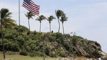 Un hombre aparece cerca de un mástil con la bandera de Estados Unidos a media asta en la isla Little St. James de las Islas Vírgenes estadounidenses, propiedad de Jeffrey Epstein, 14 de agosto de 2019. Ahora apodada Isla Pedófilo, atrae a los turistas desde que el financista acusado de tráfico sexual aparentemente se suicidó en una cárcel en Nueva York