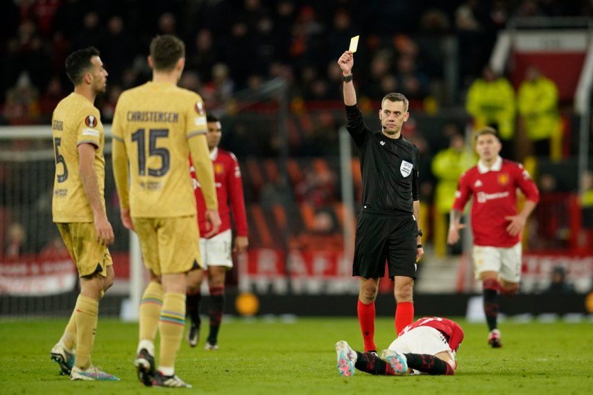 El árbitro Clement Turpin le muestra la tarjeta amarilla a Sergio Busquets, del Barcelona, por una falta a Alejandro Garnacho, del Manchester United, durante el partido de vuelta de su serie de la Liga de Europa, el jueves 23 de febrero de 2023, en Manchester, Inglaterra.&nbsp;
