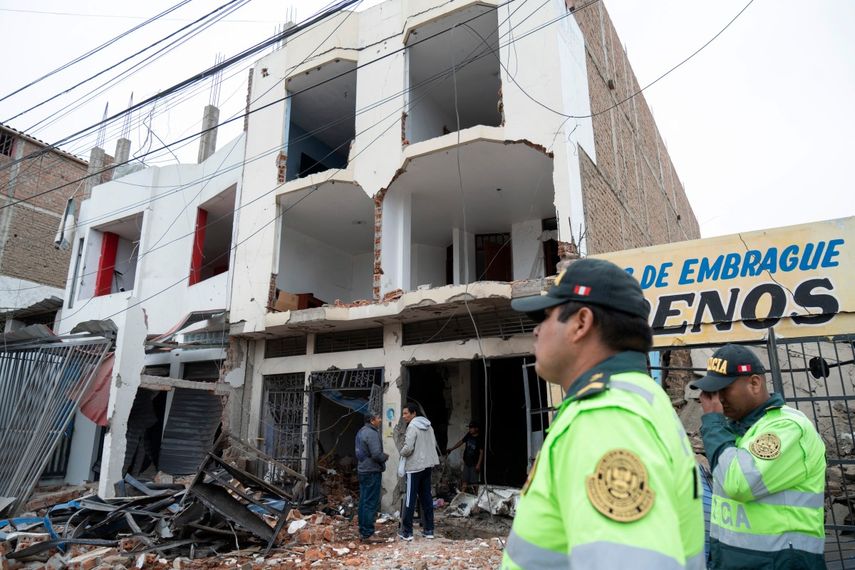 Policías vigilan los restos de una vivienda que sufrió un ataque con dinamita durante enfrentamientos entre organizaciones criminales en la ciudad de Trujillo, norte de Perú, el 15 de agosto de 2025.