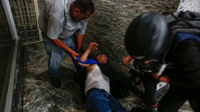 Trabajadores de la prensa han sido atacados y robados por los cuerpos de seguridad del Estado. Aquí,&nbsp;El asistente de cámara de TV&nbsp;Venezuela&nbsp;noticias, Larry Arvelo (c) es auxiliado por otros periodistas.