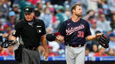 l pitcher de los Nacionales de Washington Max Scherzer (derecha) espera a ser revisado cerca del umpire de plato Tim Timmons tras el primer inning del juego de la MLB que enfrentó a su equipo con los Filis de Filadelfia