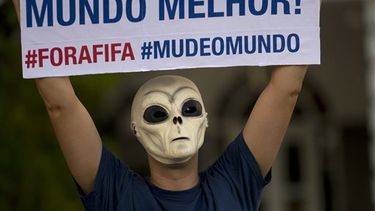 Un manifestante enmascarado sostiene un cartel que dice, por un mundo mejor, fuera FIFA, cambien el mundo, durante una protesta contra el Mundial de fútbol, realizada en Río de Janeiro, el sábado 25 de enero de 2014 (AP Foto/Silvia Izquierdo)