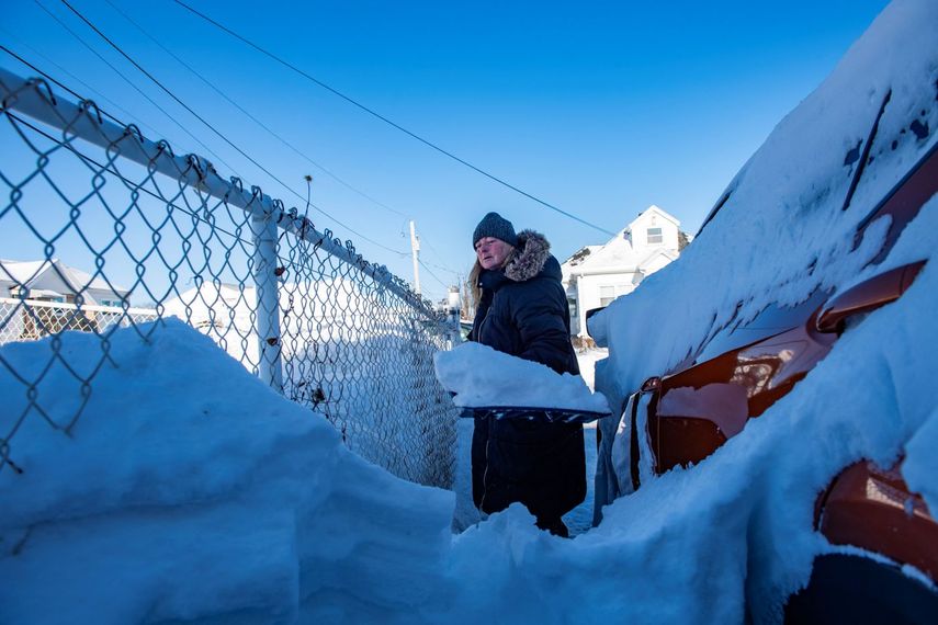 Una mujer trata de limpiar la nieve para poder sacar su auto dentro de la nieve en Massachusetts.