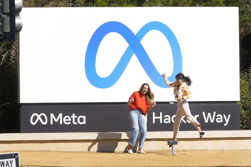 Jóvenes frente al logo de Meta, la empresa matriz de Facebook, Instagram, WhatsApp y Threads.