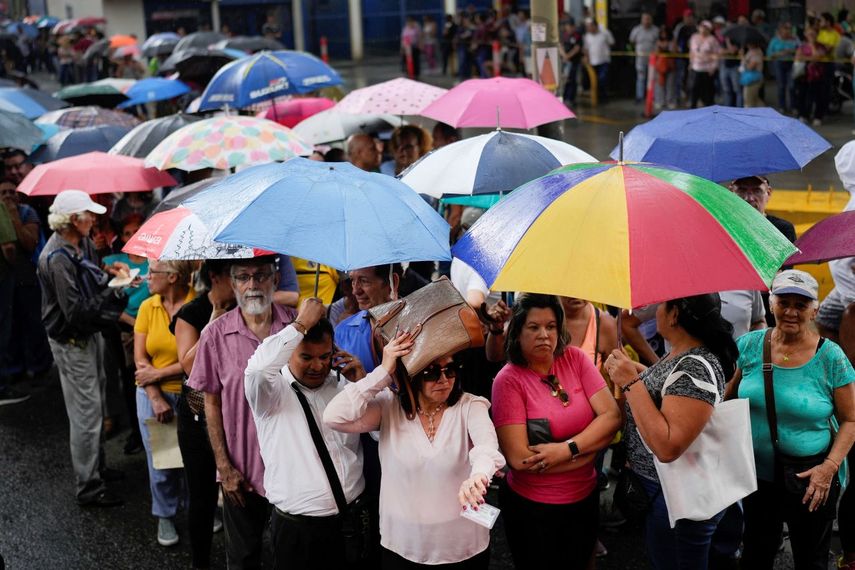Personas hacen fila en medio de una fuerte lluvia para votar en las elecciones primarias de la oposición en Caracas, Venezuela, el domingo 22 de octubre de 2023.