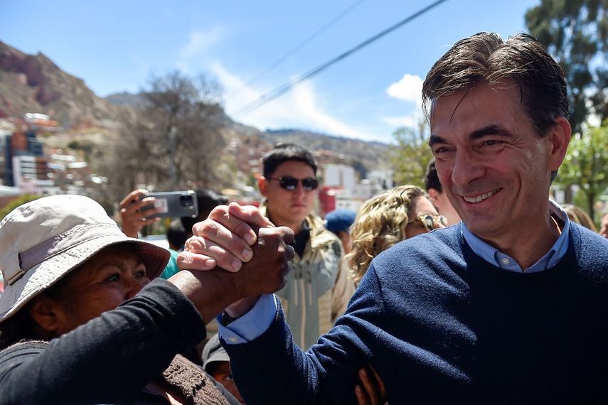 El candidato presidencial de Bolivia por el Partido Demócrata Cristiano (PDC), Rodrigo Paz, saluda a un simpatizante a su llegada a un colegio electoral mientras acompaña a su hija Catalina (fuera de cuadro) a votar durante la segunda vuelta de las elecciones presidenciales en La Paz el 19 de octubre