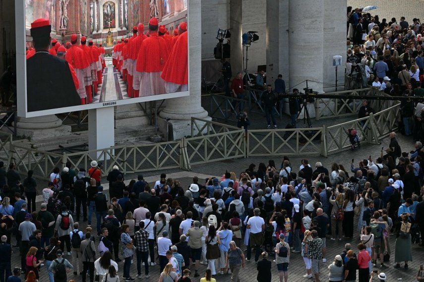 Los visitantes observan la procesión del cardenal a la Capilla Sixtina, proyectada en una pantalla, antes del cónclave, en la Plaza de San Pedro del Vaticano, el 7 de mayo de 2025.