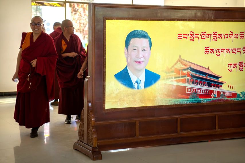 Varios monjes pasan junto a un retrato del presidente chino Xi Jinping y la plaza Tiananmén de Beijing en el Colegio Budista Tibetano.