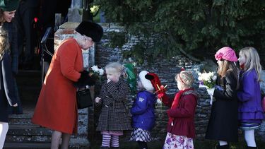 La reina Isabel II de Gran Bretaña recibe flores de parte de niños mientras la Duquesa de Cambridge, a la izquierda, los observa luego de que la familia real británica acudió a la ceremonia de Navidad en la iglesia de St. Mary (AP)