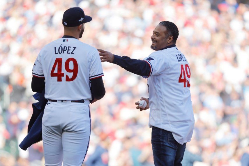 El exlanzador de los Mellizos de Minnesota, Johan Santana (derecha), habla con su compatriota venezolano Pablo López, antes de hacer el primer lanzamiento del tercer juego de la Serie Divisional de la Liga Americana, contra los Astros de Houston.