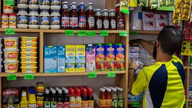Un empleado de una tienda organiza productos alimenticios en un estante con los carteles de precios de los productos en bolívares en Caracas, Venezuela el 28 de septiembre de 2021.