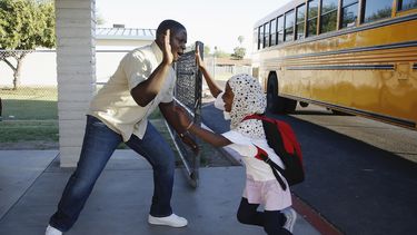 Samuel Lavi, izquierda, un congole&ntilde;o que es asistente de docencia y enlace con las familias, saluda a la alumna de primer grado Kediga Ahmed al arribar a la Escuela Valencia para Recienvenidos en Phoenix, Arizona.&nbsp;