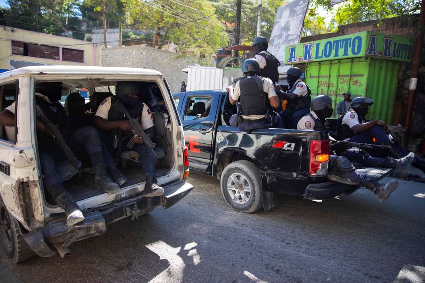 Unos policías vigilan tras recuperar los cuerpos de dos periodistas que fueron asesinados por pandillas en Puerto Príncipe, Haití, el 7 de enero de 2022.