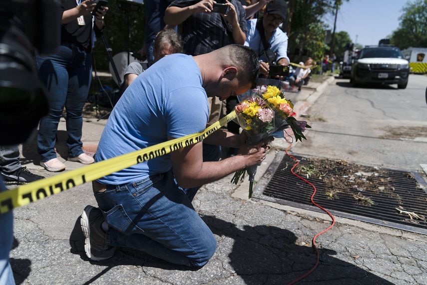 Joseph Avila (izquierda) reza mientras sostiene unas flores el miércoles 25 de mayo de 2022, en honor a las víctimas del tiroteo en la escuela primaria Robb, en Uvalde, Texas. 
