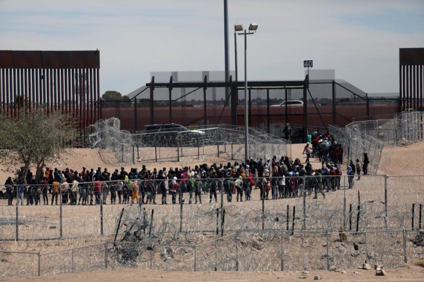 Migrantes hacen fila para ser trasladados por la Patrulla Fronteriza de Estados Unidos después de haber cruzado el río Bravo en El Paso, Texas, el 18 de abril de 2024.