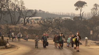 En esta imagen, distribuida por el Departamento de Defensa de Australia, evacuados caminan hacia la playa para subir a barcas que los llevar&aacute;n al HMAS Choules, un barco de la Marina, el 3 de enero de 2020, en Mallacoota, Victoria, Australia.&nbsp;