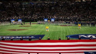 Los equipos se alinean para los himnos nacionales antes del partido de béisbol entre los Dodgers de Los Ángeles y los Cachorros de Chicago en la Serie de Tokio de la MLB en el Tokyo Dome en Tokio el 18 de marzo de 2025. En el medio del terreno de juego, se observa un Pikachu del famoso animé y videojuego, Pokémon