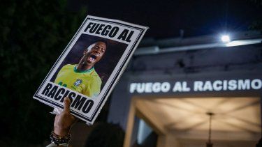 En foto del 23 de mayo del 2023, un manifestante sostiene una imagen del futbolista brasileño Vinicius Junior con un mensaje en portugués que se traduce: Pelea contra el racismo durante una manifestación por el racismo contra el jugador.