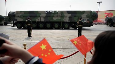 Espectadores ondean banderitas chinas mientras vehículos militares con misiles balísticos DF-41 pasan durante un desfile en ocasión del 70mo aniversario de la fundación del Partido Comunista de China en Pekín.