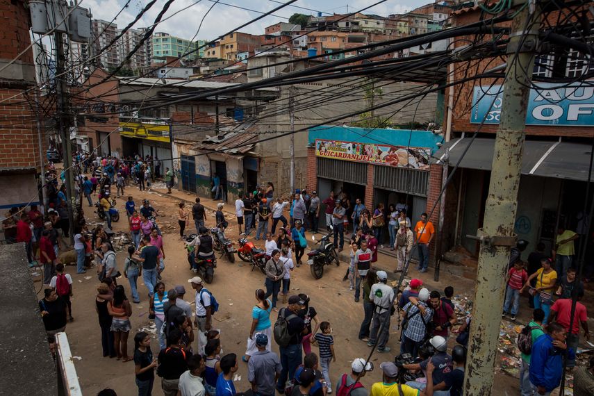 Docenas de personas permanecen hoy, viernes 21 de abril de 2017, a las afueras de varios comercios que fueron saqueados anoche en la parroquia popular El Valle, en el oeste de Caracas
