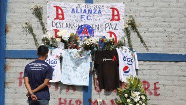 Un aficionado del Alianza se ve parado ante las ofrendas colocadas en memoria de aficionados muertos en una estampida en el estadio Cuscatlán ante el estadio, en San Salvador, El Salvador, el lunes 22 de mayo de 2023.