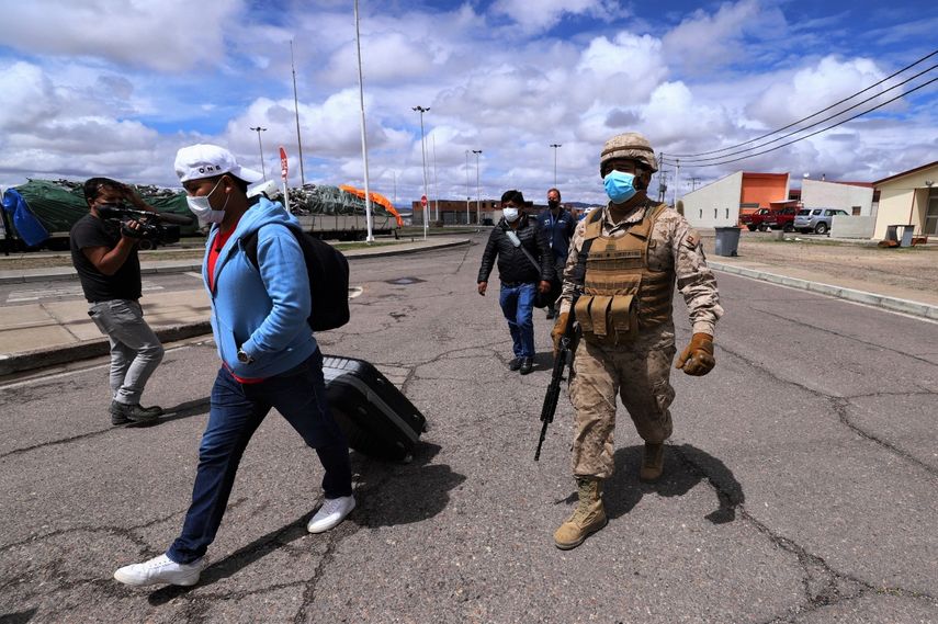 Un soldado chileno escolta a migrantes a las instalaciones policiales en Colchane, Chile, en la frontera con Bolivia. La frontera chilena está cerrada después de que el sábado entrara en vigor una nueva ley de migración. Esa ley ordena a policías y militares redireccionar a la frontera a cualquier extranjero que evada el control migratorio.