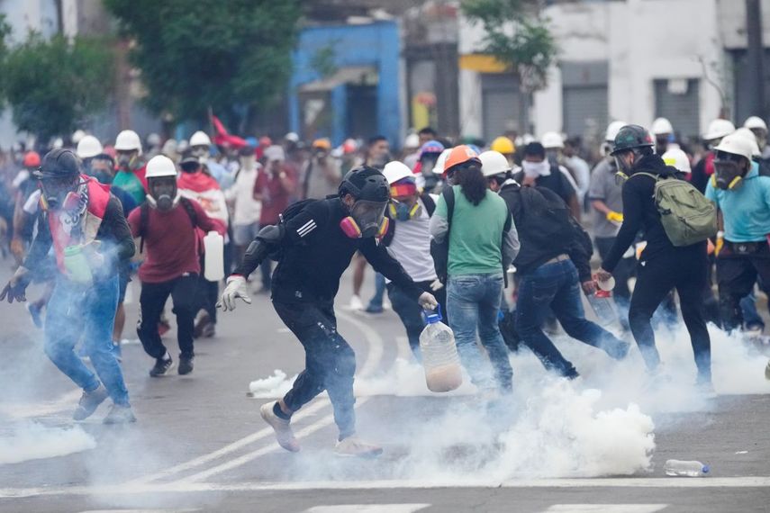 Varios manifestantes antigubernamentales recogen cartuchos de gas lacrimógeno que les lanzó la policía para disolverlos en Lima, Perú, el sábado 28 de enero de 2023.