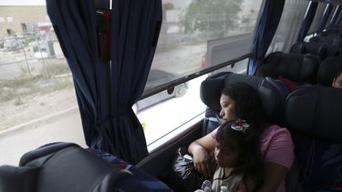 Una mujer centroamericana y su hijo esperan en un autobús después de ofrecerse como voluntarios para volver a su país.