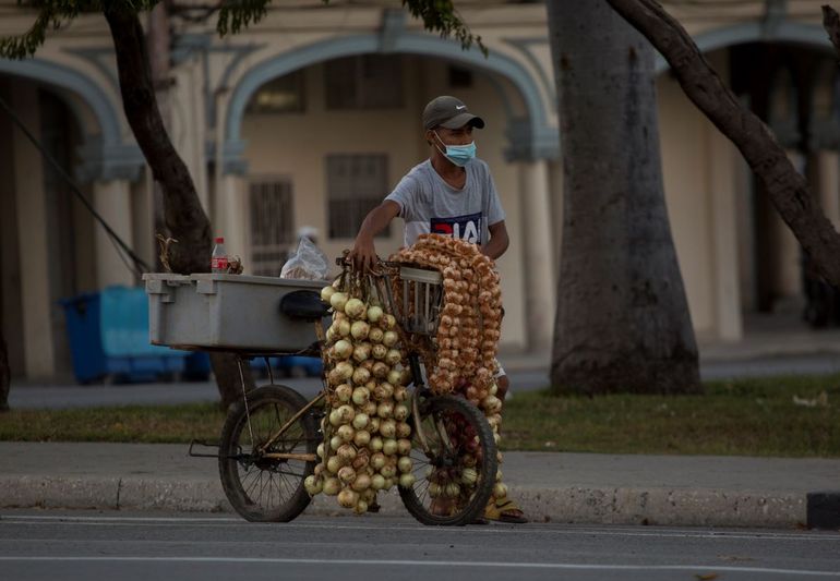 Un hombre con una mascarilla protectora vende ajos y cebollas en La Habana, Cuba, el jueves 30 de diciembre de 2021, en medio de la nueva pandemia de coronavirus. 