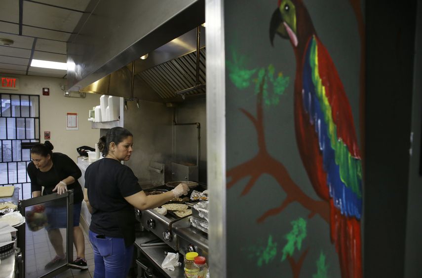 La salvadoreña Anna López (zq) y la hondureña María Erazo trabajando en la cocina de un restaurante de Chelsea, Massachusetts.