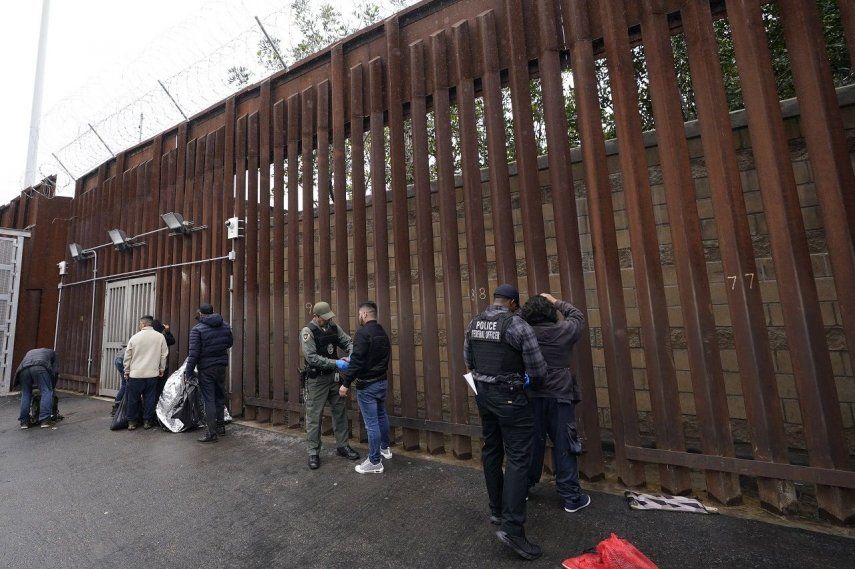 Oficiales federales estadounidenses le quitan las esposas a hombres antes de liberarlos cerca de la muralla fronteriza en San Diego el 15 de marzo de 2023.