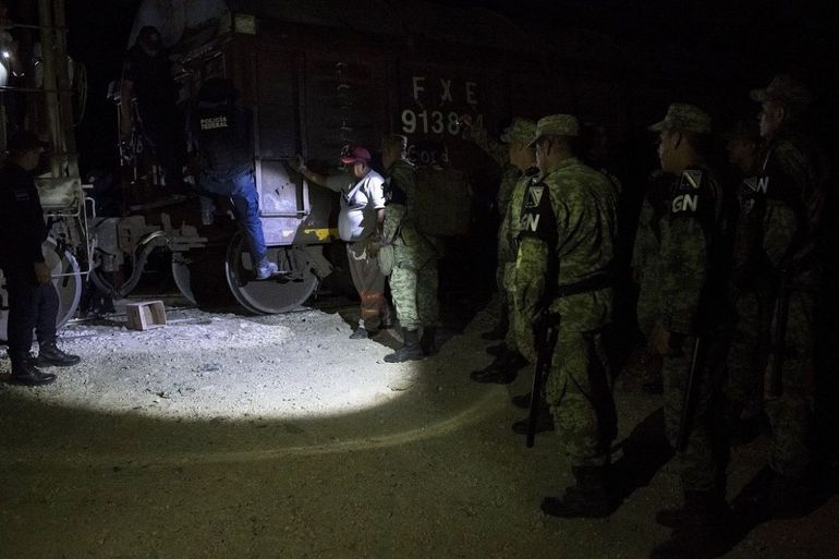 Efectivos de la nueva Guardia Nacional detienen a migrantes que viajaban de polizones en lo alto de los vagones del tren de carga conocido como 