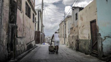 Un hombre arrastra una carretilla cargada de agua por una calle en Santiago de Cuba, Cuba.