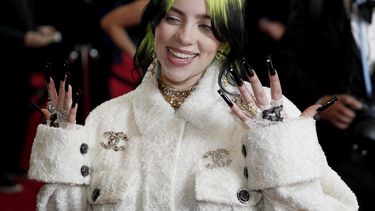 La cantante Billie Eilish, con el cabello teñido de verde fosforescente, lleva un abrigo color blanco de la firma Chanel.  