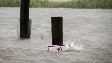 Un anuncio en una rampa para botes aparece casi inundado durante la marea alta, mientras el huracán Dorian por la costa este de EEUU.