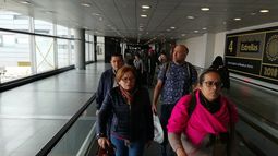 El teniente coronel venezolano Edgar Alejandro Lugo Pereira (2do der.) y sus dos acompañantes, Mildred Josefina Plaza Hernández y Jenny Yamel Rivas González (al frente), son conducidos por un oficial de Migración Colombia en el Aeropuerto Internacional El Dorado, en Bogotá.