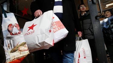 Clientes salen de las tiendas con bolsas de compras.