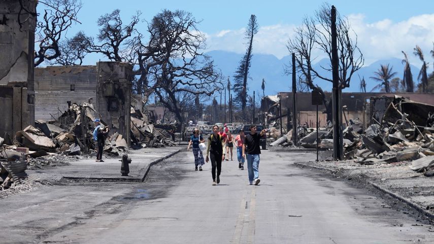 Personas caminan en medio de una calle observando los daños causados por un incendio forestal, el viernes 11 de agosto de 2023, en Lahaina, Hawai.&nbsp;