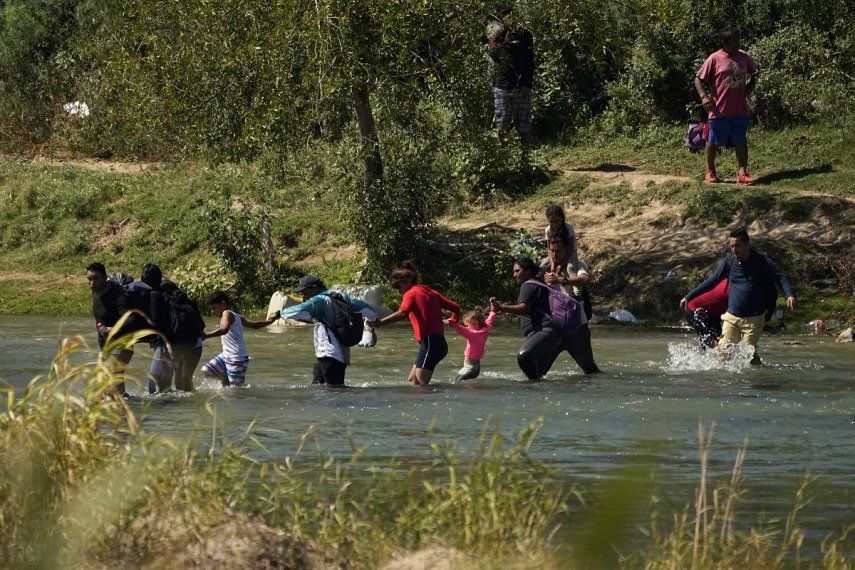 Migrantes cruzan de la mano el Río Bravo desde México a Estados Unidos, el 21 de septiembre de 2023, en Eagle Pass, Texas. 