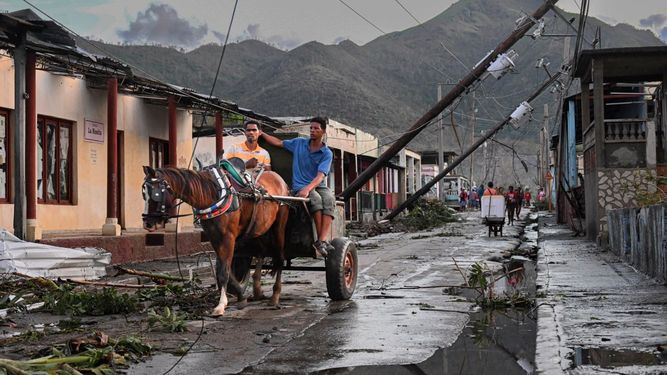 Los residentes de El Cobre, en la provincia de Santiago de Cuba, transitan en medio de las líneas eléctricas caídas tras el paso del huracán Melissa, el 29 de octubre de 2025.