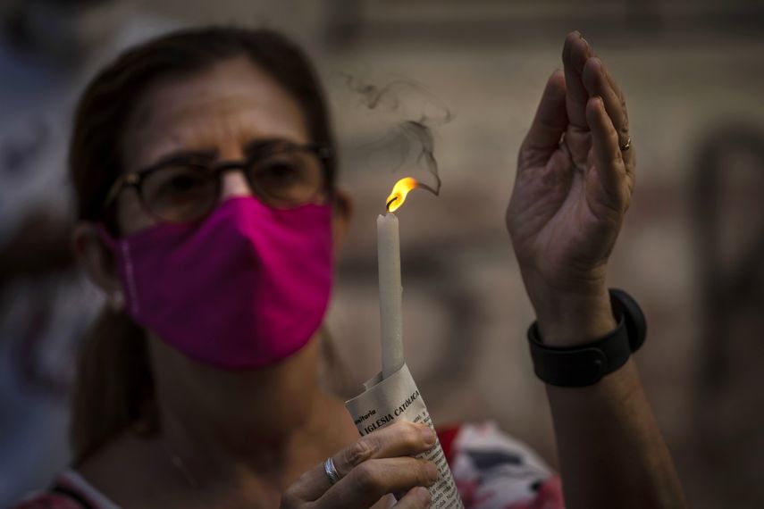 Una mujer con mascarilla sostiene una vela encendida durante una misa cat&oacute;lica transmitida por radio en honor a la Virgen de la Caridad del Cobre, en su fiesta en La Habana, Cuba, el martes 8 de septiembre de 2020.