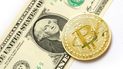 Una moneda de bitcoin junto a un billete de dólar. Una moneda de bitcoin junto a un billete de dólar.