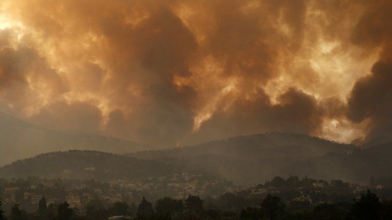 En esta imagen de archivo del viernes 6 de agosto de 2021, el humo se extiende sobre el monte Parnitha durante un incendio forestal en el poblado de Ippokratios Politia, Grecia, unos 35 kilómetros (21 millas) al norte de Atenas. Miles de personas huyeron de los incendios forestales descontrolados en Grecia y Turquía, donde una prolongada ola de calor ha secado los bosques, y el fuego amenazaba zonas pobladas e instalaciones eléctricas. 