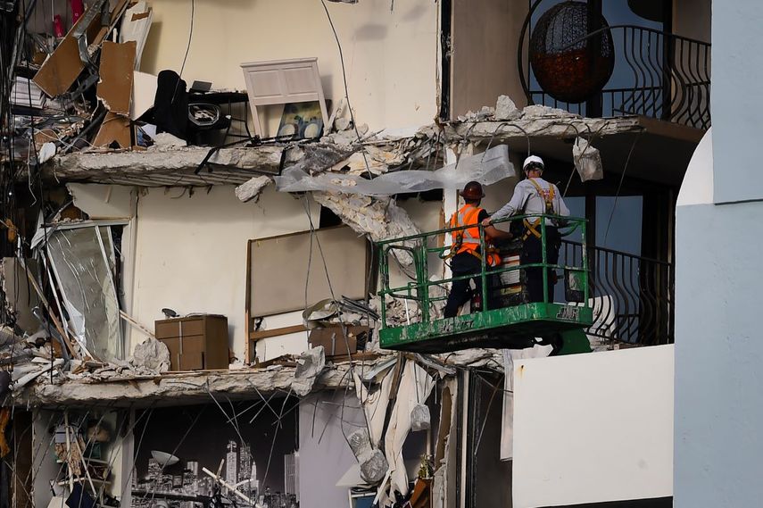Trabajadores de rescate en una grúa inspeccionan los restos de un edificio parcialmente derrumbado en Surfside al norte de Miami Beach, Florida.