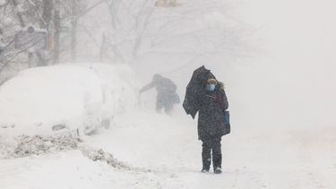 Los autos están casi enterrados en nieve, mientras dos personas caminan durante una tormenta de nieve en el área de Hamilton Heights en el distrito de Manhattan de la ciudad de Nueva York el 23 de febrero de 2026.