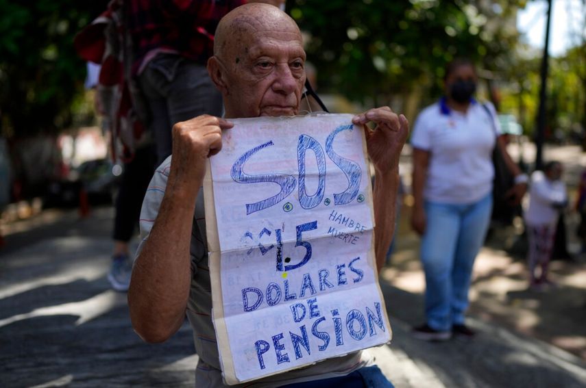 Carlos Blanco, de 84 años, supervisor de ambulancias retirado, sostiene un cartel que anuncia el pago mensual de su pensión de $1.50 dólares durante una protesta en que demandaban un incremento en los pagos en medio de una inflación récord en Caracas, Venezuela.&nbsp;