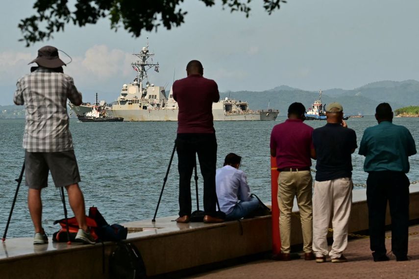 La gente observa y toma fotos del USS Gravely, un barco de guerra de la Marina de los Estados Unidos, al salir del Puerto de Puerto España el 30 de octubre de 2025.