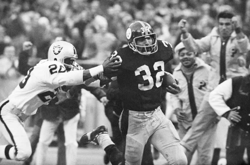 Franco Harris (32) de los Steelers de Pittsburgh elude a Jimmy Warren de los Raiders de Oakland al anotar un touchdown de 42 yardas tras atrapar un pase desviado, el 23 de diciembre de 1972.
